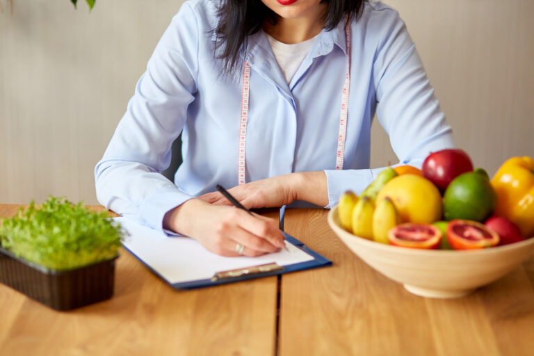 Nutritionist, dietitian woman writing a diet plan, with healthy vegetables and fruits